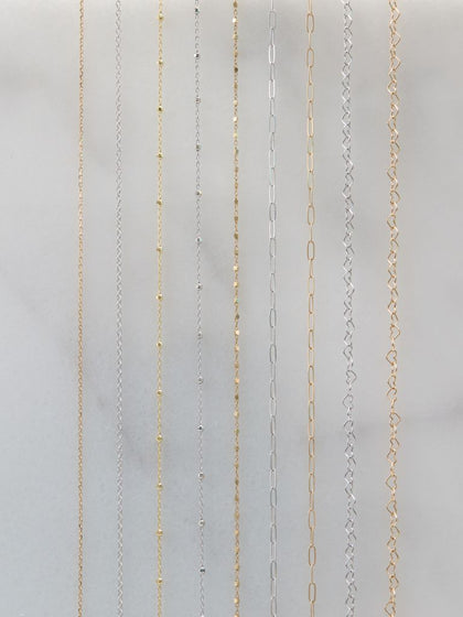A selection of 14K gold permanent jewelry chain styles in yellow and white gold