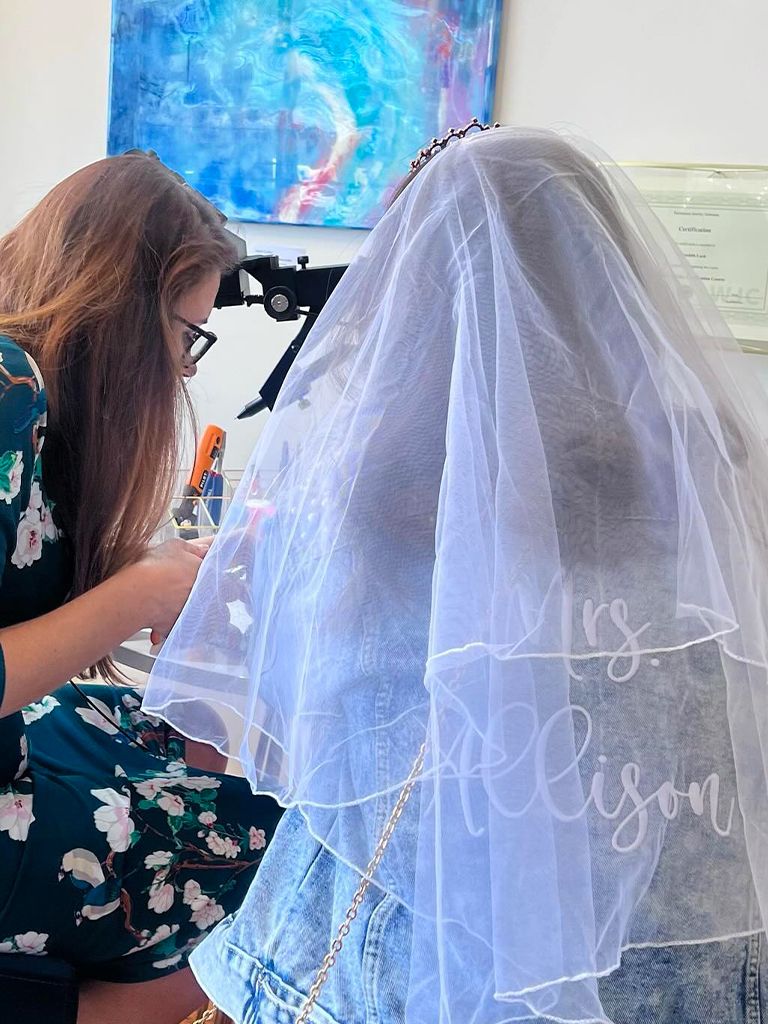 A bride in a “Mrs.” veil having her permanent bracelet welded at Moonrise Jewelry