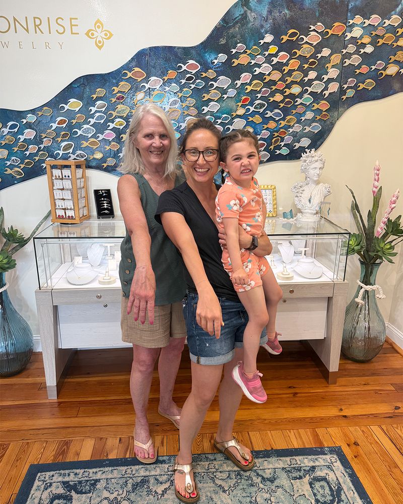 A grandmother, mother, and young daughter showing off their matching permanent bracelets in the Moonrise studio