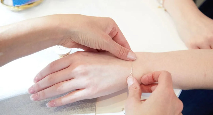 A Moonrise jeweler measuring a delicate chain against a customer's wrist for a custom fit